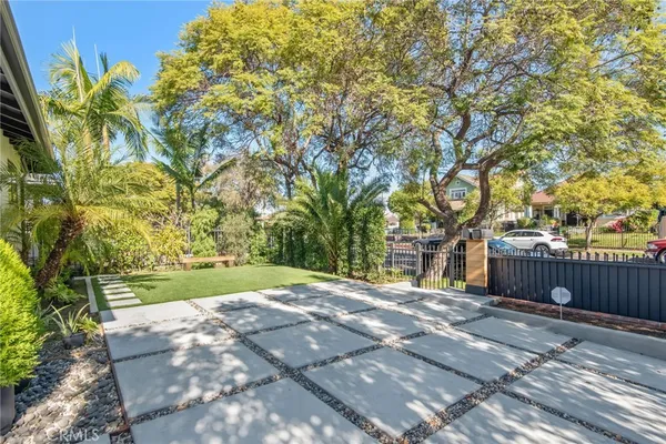 a big yard with large trees and wooden fence