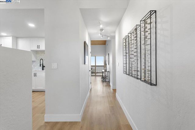 a view of a hallway with wooden floor and a living room