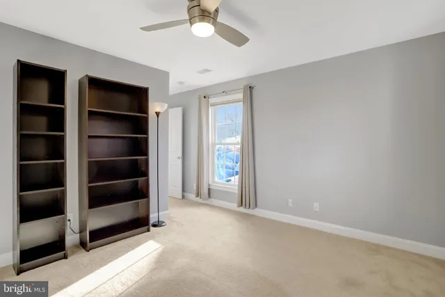 a view of an empty room with a window and kitchen view