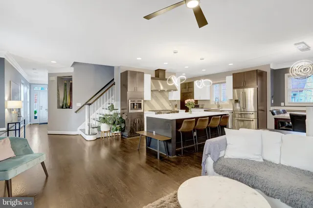 a living room with furniture kitchen view and a wooden floor
