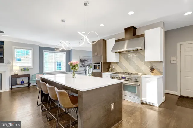 a kitchen with stainless steel appliances granite countertop a stove a refrigerator a sink dishwasher a dining table and chairs with wooden floor