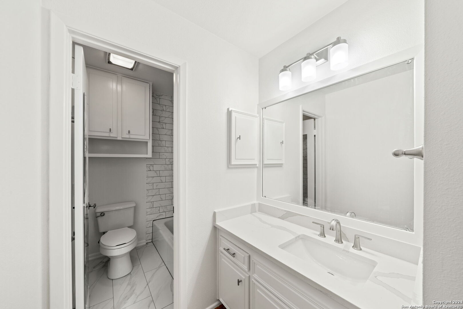 6106 Vance Jackson Road, Unit 50 San Antonio, TX 78230 - Photo 16 of 30 a bathroom with a granite countertop toilet a sink and a mirror