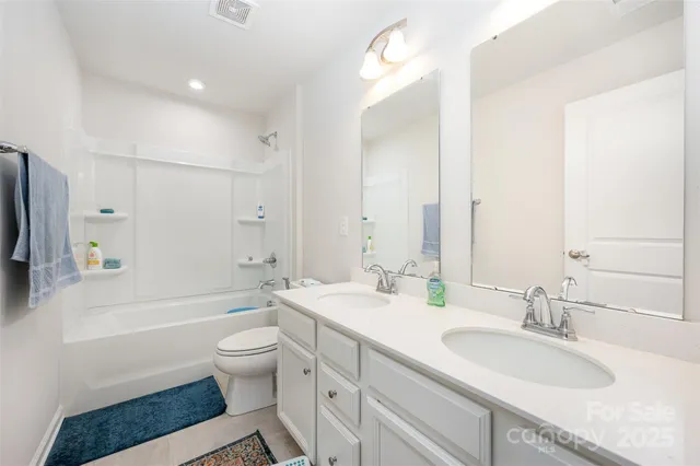 a bathroom with a granite countertop sink a toilet a mirror and shower