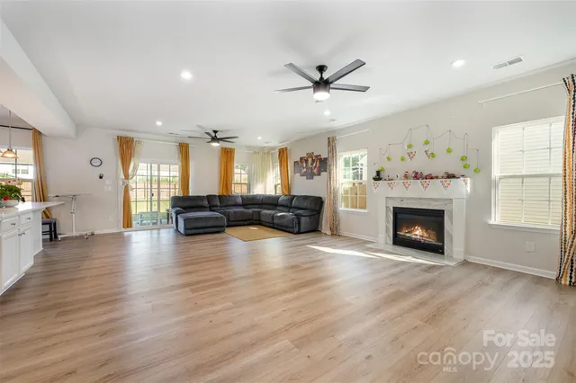 a view of a livingroom with a fireplace a ceiling fan and windows