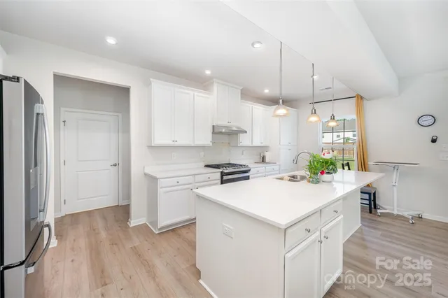 a kitchen with a stove a sink a center island and wooden floor