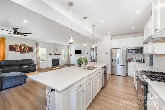a large kitchen with kitchen island a stove a sink a refrigerator and a living room view
