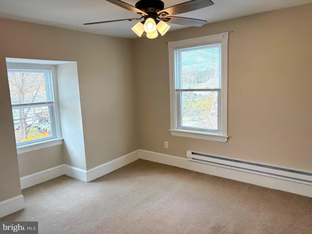 an empty room with windows and fan