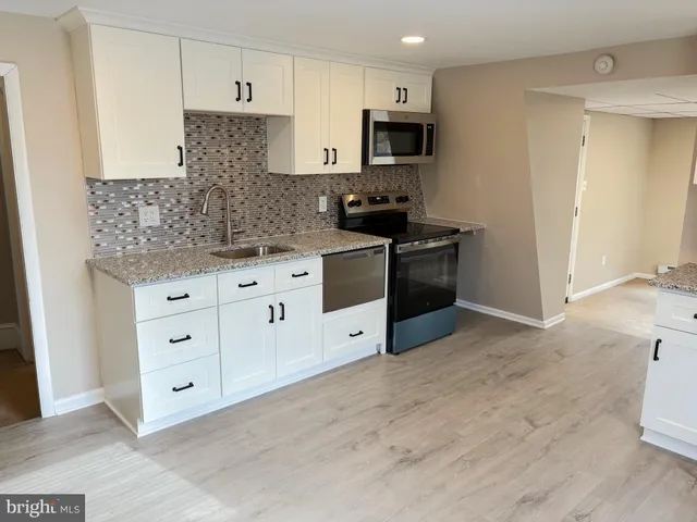 a kitchen with stainless steel appliances white cabinets a sink and a stove