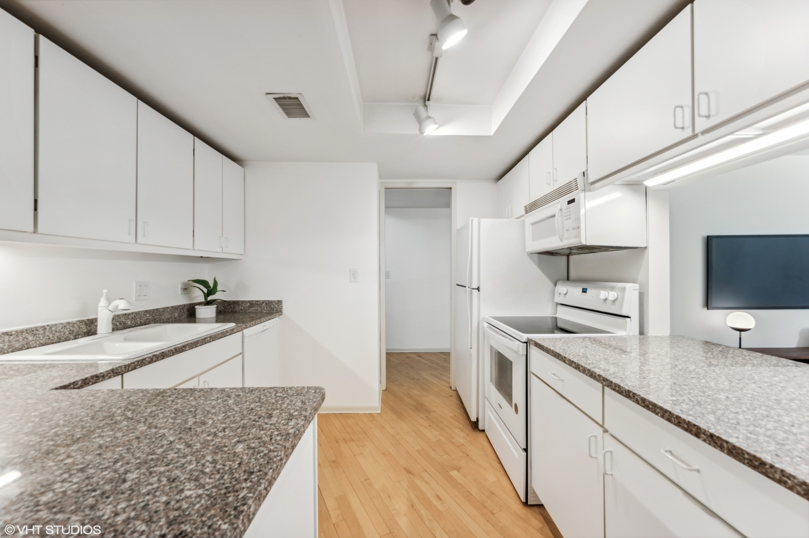 40 East Delaware Place, Unit 301 Chicago, IL 60611 - Photo 13 of 21 a large white kitchen with stainless steel appliances granite countertop a sink dishwasher a stove and white cabinets with wooden floor