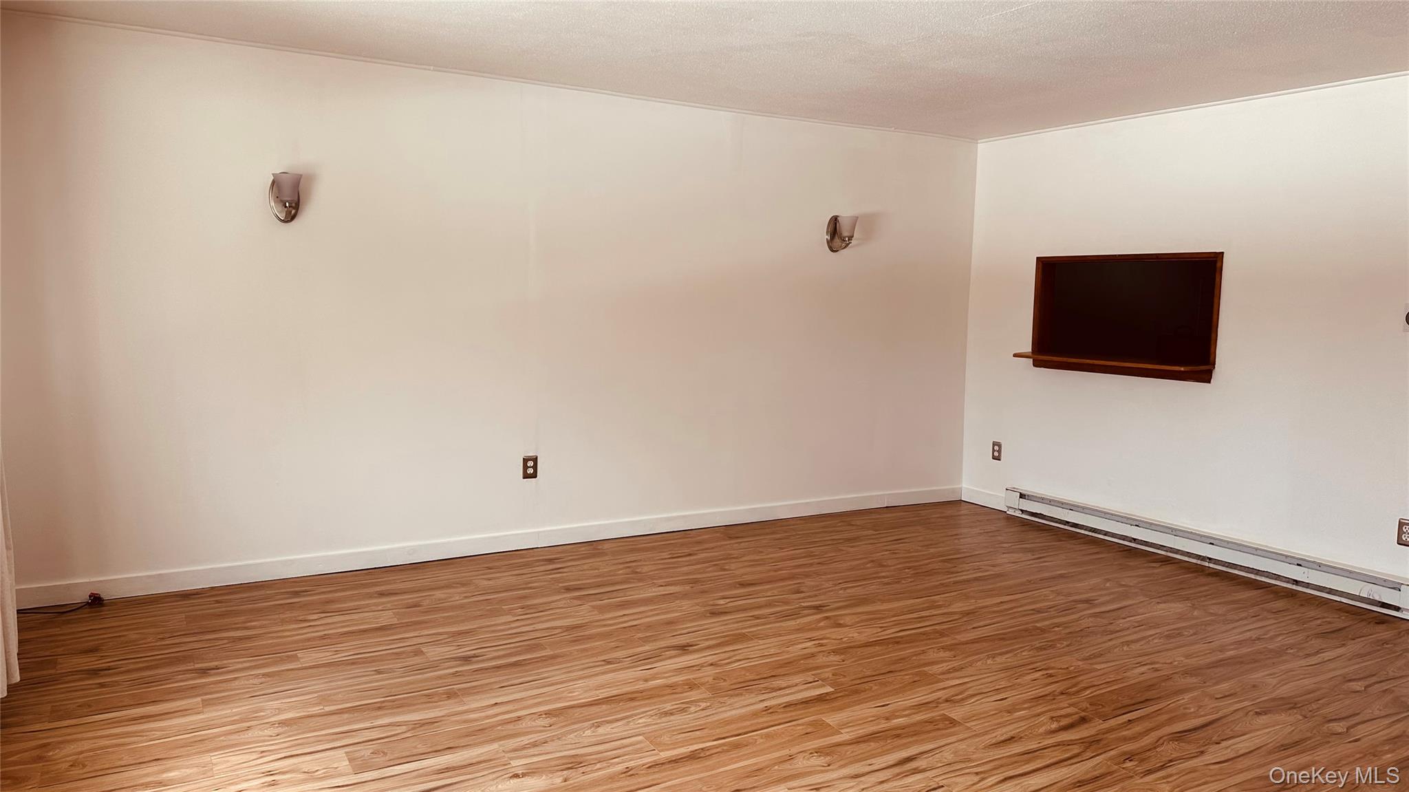 881 Albany Post Road, Unit 17 New Paltz, NY 12561 - Photo 3 of 15 a view of an empty room with wooden floor and a flat screen tv