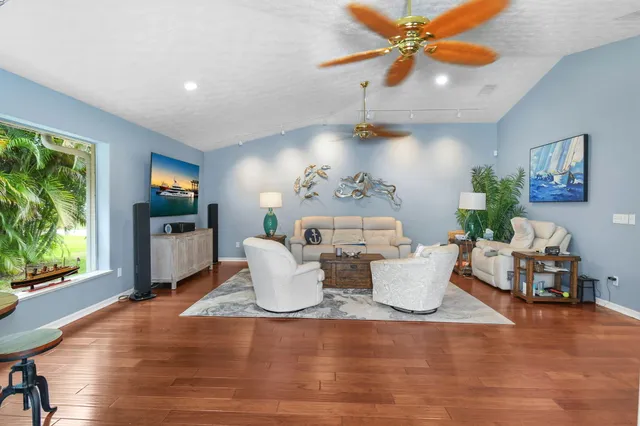 a living room with furniture and dining area with wooden floor