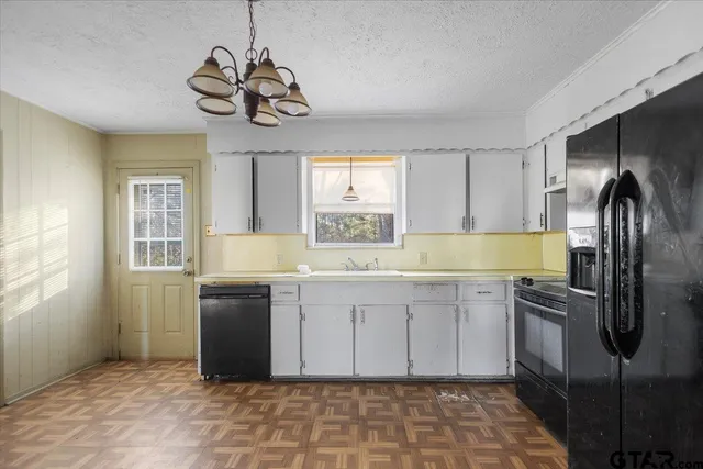 a kitchen with stainless steel appliances granite countertop a sink a stove a refrigerator a washer dryer and a window