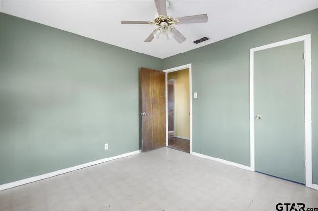 an empty room with a ceiling fan and a chandelier fan