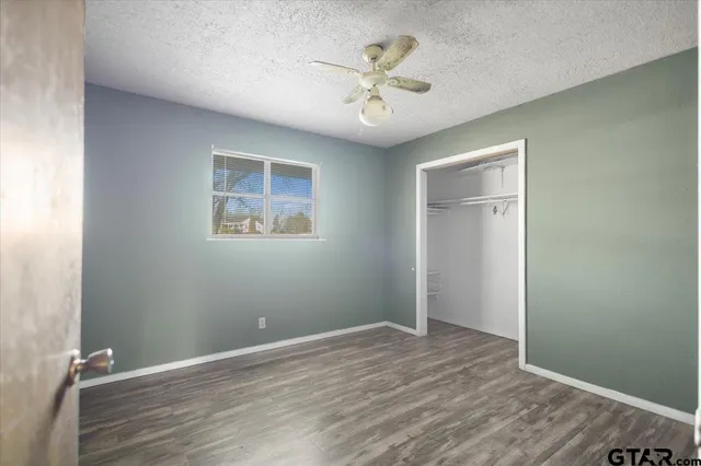 an empty room with wooden floor and a ceiling fan