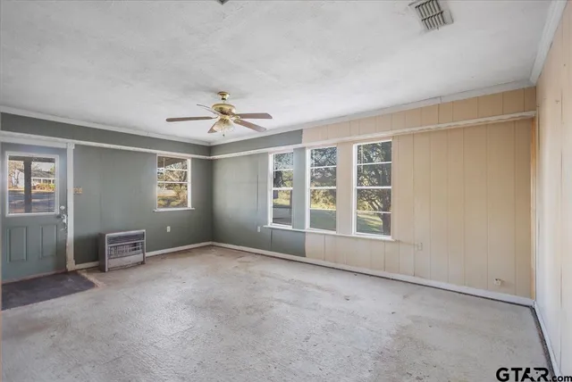 an empty room with chandelier fan and windows