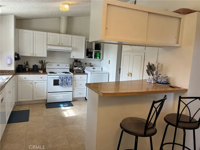 a kitchen with stainless steel appliances a sink a stove a table and chairs