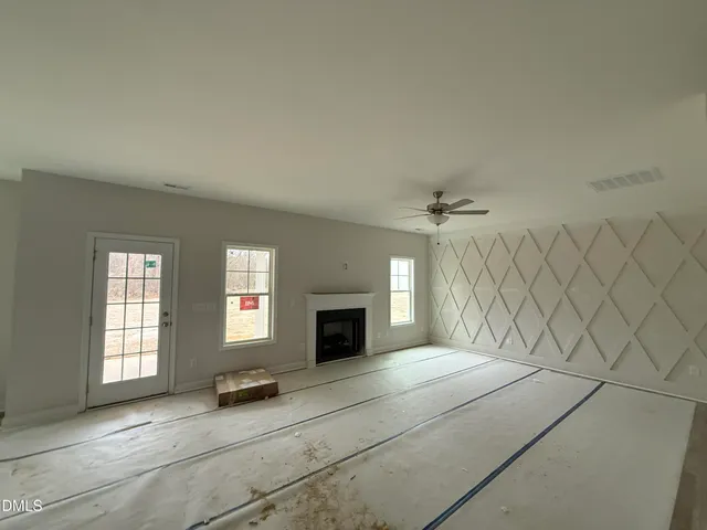 an empty room with windows and fireplace
