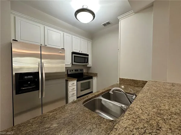 a kitchen with granite countertop a sink stainless steel appliances and cabinets