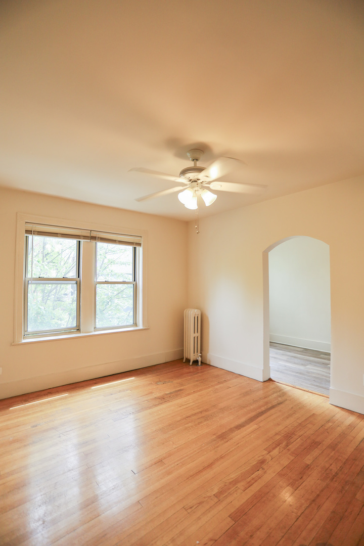 1100 West Roscoe Street, Unit 11 Chicago, IL 60657 - Photo 5 of 9 a view of an empty room with wooden floor and a window