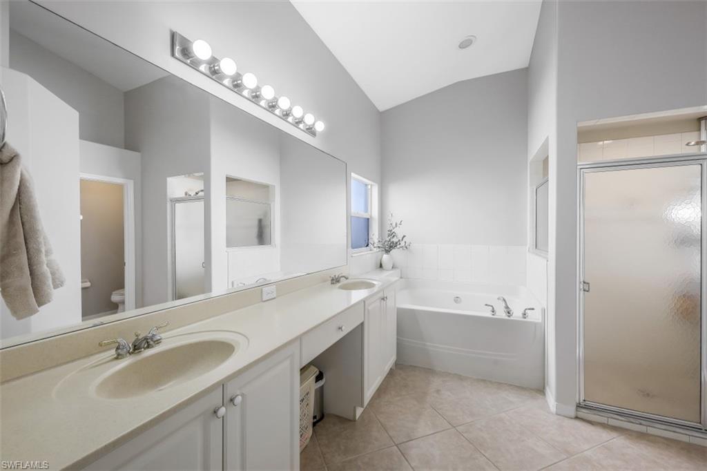 21641 Helmsdale Run Estero, FL 33928 - Photo 15 of 35 a bathroom with a tub a double vanity sink and a mirror
