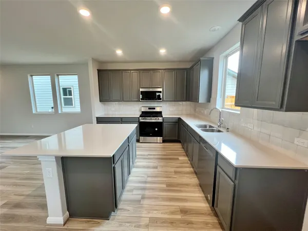 a large kitchen with a large counter top stainless steel appliances and cabinets
