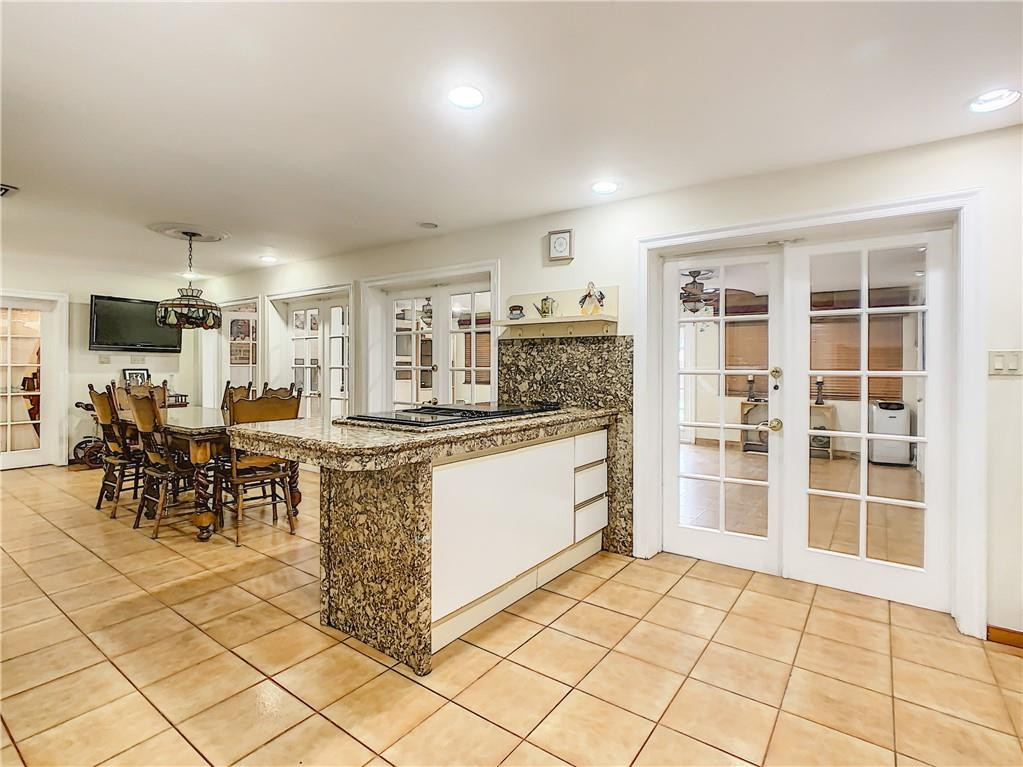 1234 Funston Street Hollywood, FL 33019 - Photo 10 of 23 a kitchen with stainless steel appliances kitchen island granite countertop a refrigerator a stove a dining table and chairs with wooden floor
