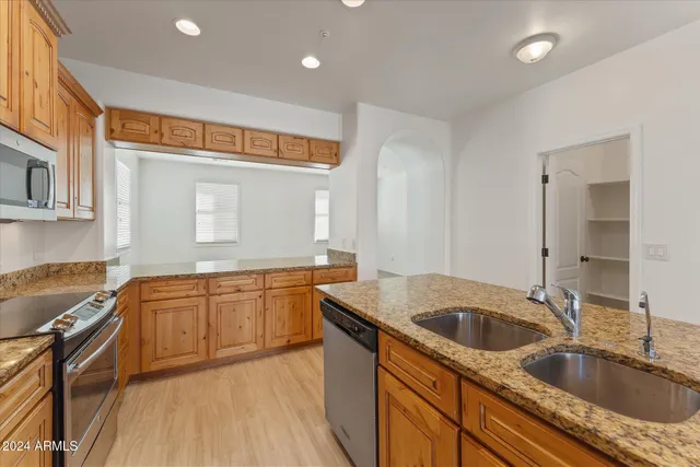 a kitchen with granite countertop a sink and cabinets with wooden floors