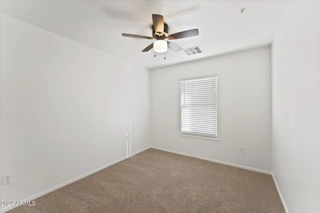 an empty room with a window and a ceiling fan