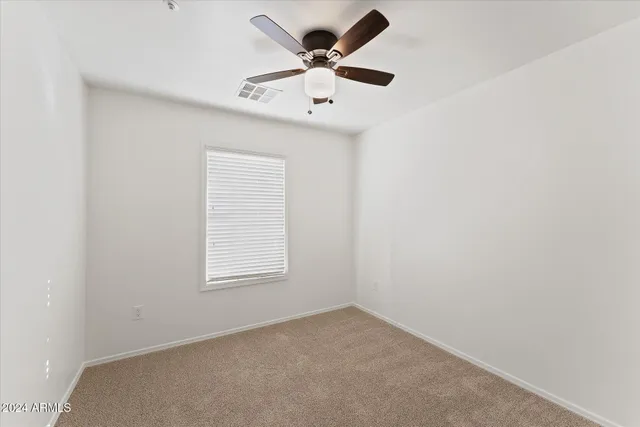 an empty room with windows and ceiling fan