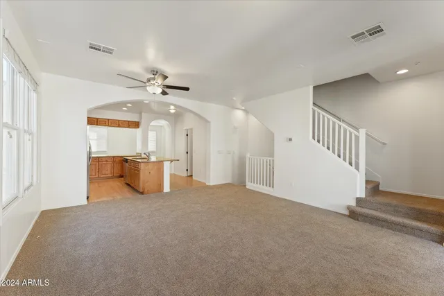 a view of a livingroom with a ceiling fan and kitchen view
