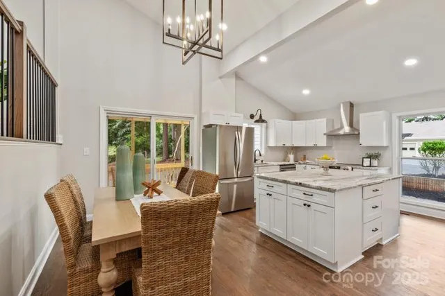 a kitchen with stainless steel appliances granite countertop a stove refrigerator a sink dishwasher a dining table and chairs with wooden floor