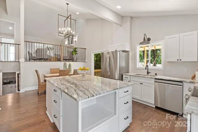 a open kitchen with stainless steel appliances granite countertop a kitchen island a stove a table and chairs