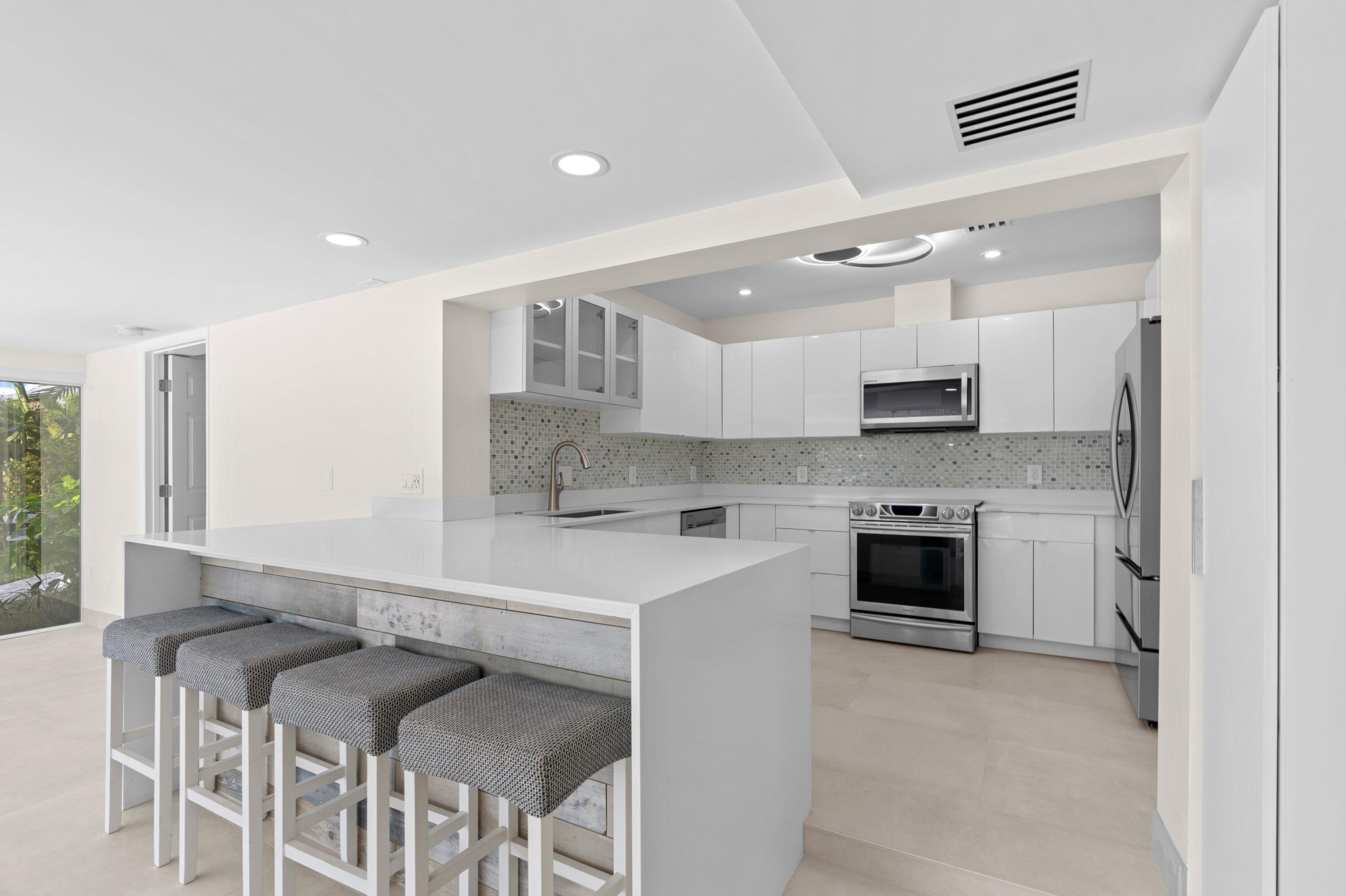 391 Southeast 7th Avenue Pompano Beach, FL 33060 - Photo 19 of 38 a large kitchen with stainless steel appliances kitchen island granite countertop a stove and a sink