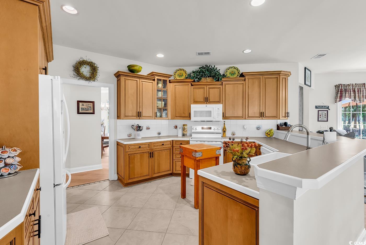 4507 Smilax Place Murrells Inlet, SC 29576 - Photo 5 of 39 Kitchen featuring white appliances, tasteful backsplash, a peninsula, brown cabinets, and recessed lighting