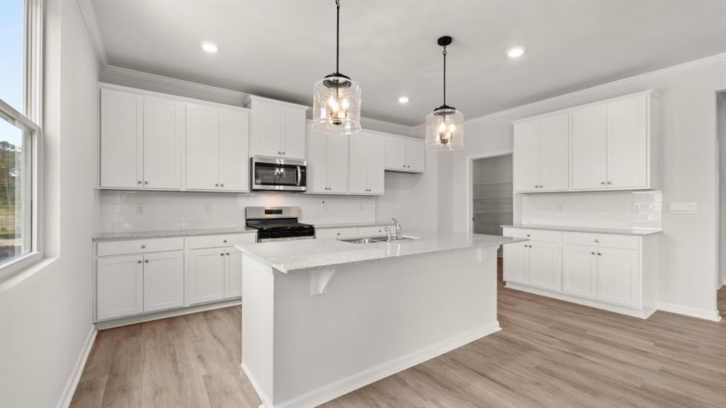 904 Sundown Point Villa Rica, GA 30180 - Photo 16 of 83 a kitchen with kitchen island a sink a stove a microwave and white cabinets