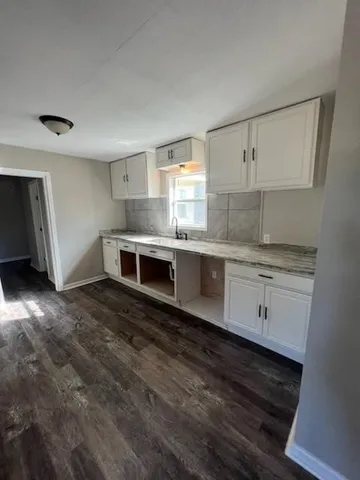 a kitchen with granite countertop a stove sink and cabinets