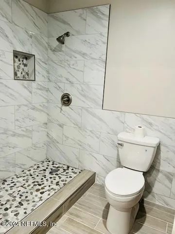 a bathroom with a granite countertop toilet sink and mirror