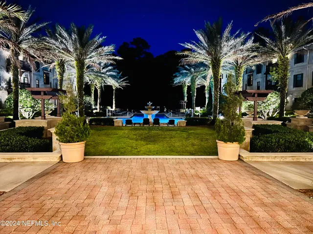 a view of a white house with a yard and potted plants