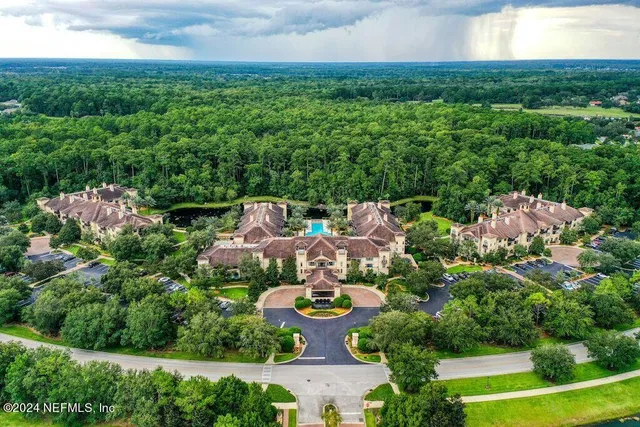 an aerial view of a residential houses with outdoor space and trees all around