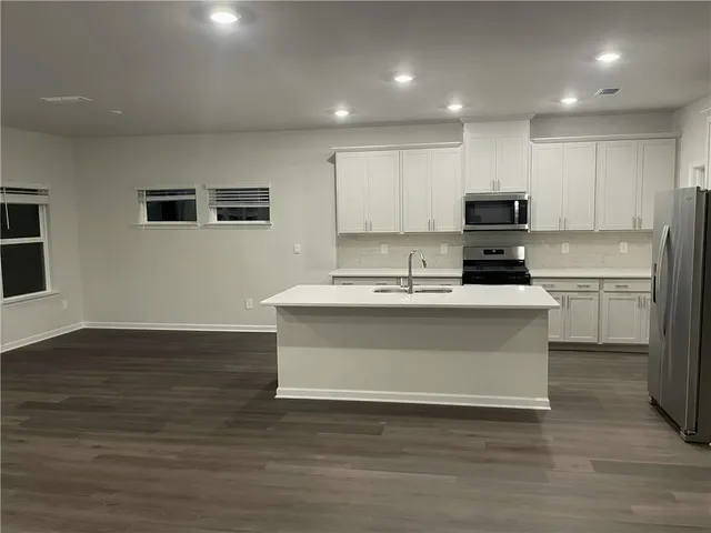 a kitchen with kitchen island sink stove and cabinets