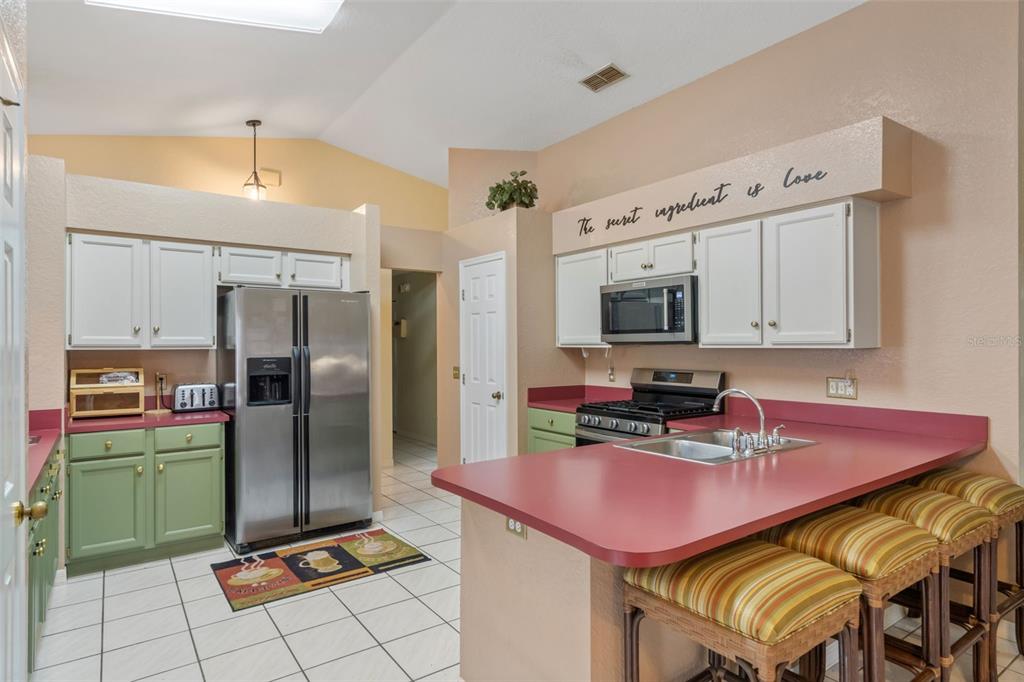 511 Marcia Loop Winter Haven, FL 33884 - Photo 14 of 46 a kitchen with stainless steel appliances a stove a sink dishwasher a refrigerator with a dining table and chairs