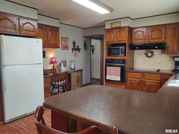 a kitchen with stainless steel appliances granite countertop a table chairs a stove a sink dishwasher and cabinets with wooden floor
