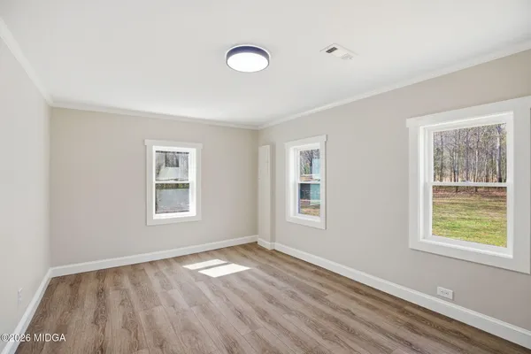 a view of empty room with wooden floor and fan