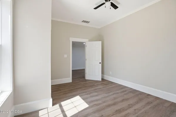 an empty room with wooden floor ceiling fan and window