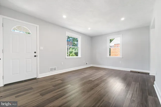an empty room with wooden floor and windows