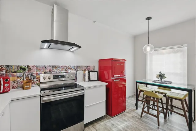 a kitchen with stainless steel appliances granite countertop a stove a refrigerator a dining table and chairs with wooden floor