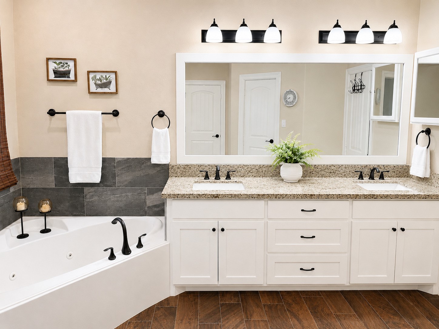 27656 Rio Blanco Drive Splendora, TX 77372 - Photo 10 of 18 This Primary Bathroom features a spacious double vanity with granite countertops, elegant dark fixtures, and ample storage. A large mirror and modern lighting enhance the space. The inviting bathtub is complemented by stylish tilework and cozy wood-look flooring.