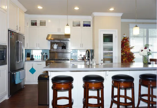 a kitchen with stainless steel appliances granite countertop a table chairs refrigerator and sink