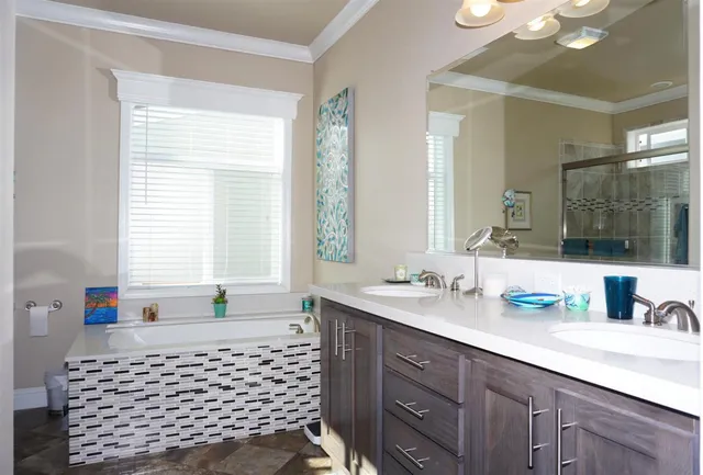 a bathroom with a double vanity sink large mirror and a bathtub