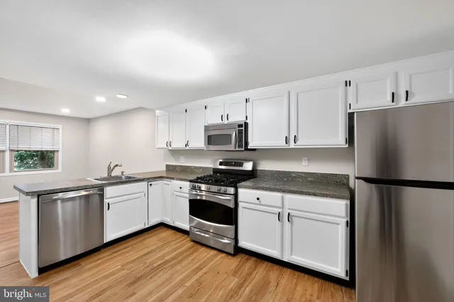 a kitchen with stainless steel appliances granite countertop a refrigerator sink and white cabinets